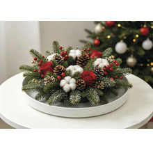 Festliches Weihnachtsgesteck mit Tannenzweigen, roten Rosen, Baumwollblüten und Tannenzapfen auf einem weißen Tablett.