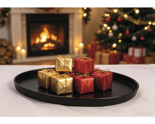 Kleine goldene und rote Geschenkboxen mit goldenen Bändern auf einem schwarzen Tablett vor einem beleuchteten Kamin und Weihnachtsbaum.