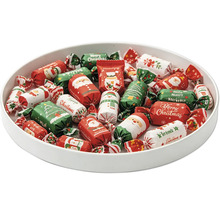 Schale gefüllt mit weihnachtlich eingepackten Süßigkeiten mit Motiven wie Weihnachtsmann, Schneemann und Tannenbaum.