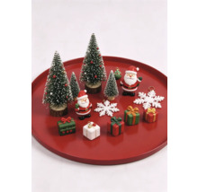 Weihnachtsdekoration-Set mit Miniatur-Tannenbäumen, Weihnachtsmann-Figuren, kleinen Geschenken und Schneeflocken auf einem roten Tablett.