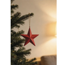 Roter Stern aus Metall als Weihnachtsbaumschmuck hängend an einer Kordel an einem grünen Tannenzweig.