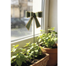 Dekorativer Blumenstecker mit Schleife in Dunkelgrün und Gold, platziert in einem Kräutertopf aus Ton auf einer Fensterbank.
