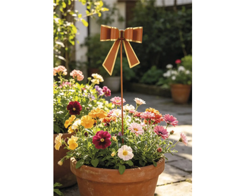Gartenstecker in Schleifenform aus Metall in einem Blumentopf mit Blumen im Garten.