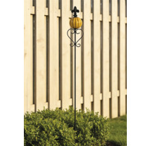 Schwarzer Gartenstecker aus Metall mit Herz-Ornament, orangefarbenem Keramik-Kürbis und Lilie vor einem Holzzaun.