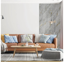 Modernes Wohnzimmer mit braunem Ledersofa, Holztisch und Vliestapete in Marmoroptik mit Goldakzenten an der Wand.