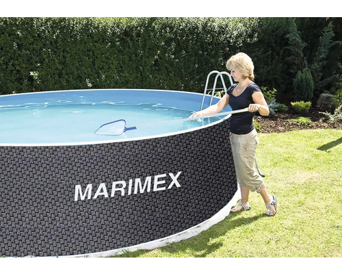 Eine Person reinigt einen runden Marimex Gartenpool in Rattanoptik mit einer Poolleiter und einem Kescher.