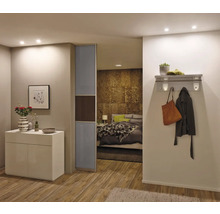 Modernes Zimmer mit weißem Sideboard, Glasschiebetür und Durchblick ins Schlafzimmer mit Wandgarderobe im Flur.
