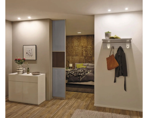 Modernes Zimmer mit weißem Sideboard, Glasschiebetür und Durchblick ins Schlafzimmer mit Wandgarderobe im Flur.
