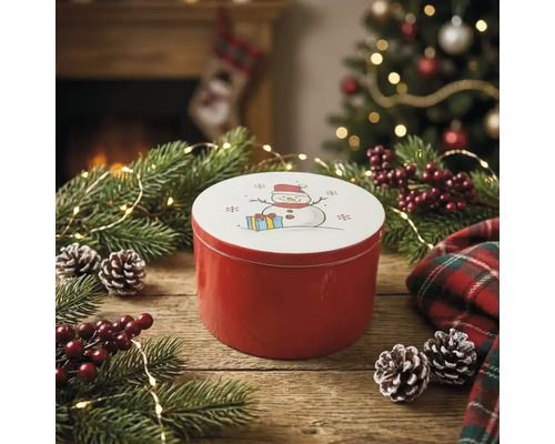 Runde rote Metalldose mit Schneemann-Motiv auf dem Deckel, dekoriert mit Tannenzweigen, Zapfen und weihnachtlichen Elementen auf Holztisch.