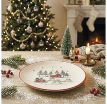 Weißer Weihnachtsteller mit rotem Rand und Illustration von Weihnachtsmann im Schlitten, Tannen und Haus in einer festlichen Wohnraumumgebung.