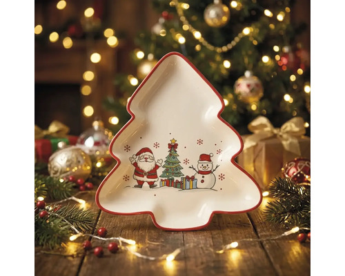 Tannenbaumförmiger Servierteller aus Keramik mit Motiven von Weihnachtsmann, Christbaum und Schneemann auf einem festlich beleuchteten Holztisch.