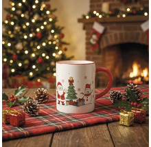Weiße Keramiktasse mit Weihnachtsmotiven auf einem karierten Läufer vor einem beleuchteten Weihnachtsbaum und einem Kamin.