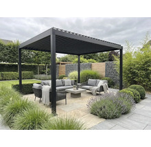 Moderne Lamellen-Pergola aus Aluminium über einer Sitzgruppe mit grauen Gartenmöbeln auf einer Steinterrasse inmitten einer Gartenanlage.