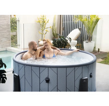 Aufblasbarer Whirlpool mit geometrischem Muster auf einer hellen Terrasse mit Pflanzen und einem Paar.