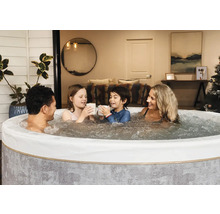Eine Familie entspannt in einem runden, aufblasbaren Whirlpool mit sprudelndem Wasser in einem gemütlichen Innenraum.