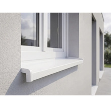 Weiße Außenfensterbank aus Kunststoff an einer hell verputzten Fassade unter einem weißen Fenster.