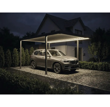 Moderner Aluminium Carport mit integrierter LED Beleuchtung, Lamellendach und geparktem SUV auf gepflasterter Einfahrt bei Nacht.