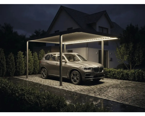 Moderner Aluminium Carport mit integrierter LED Beleuchtung, Lamellendach und geparktem SUV auf gepflasterter Einfahrt bei Nacht.