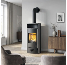Moderner schwarzer Kaminofen mit ACCENT Logo, brennendem Feuer und Steinplatte in hellem Wohnzimmer mit Holzmöbeln und Parkettboden.