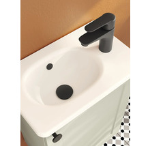 Waschbecken mit mattschwarzer Armatur und Ablauf auf einem hellen Waschtischunterschrank in einem modern gestalteten Badezimmer.