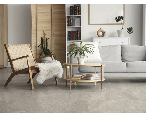 Modernes helles Wohnzimmer mit grauen Bodenfliesen in Natursteinoptik, Holzmöbeln und grauem Sofa.