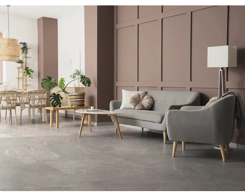 Modernes Wohnzimmer mit großformatigen grauen Bodenfliesen in Steinoptik, grauem Sofa, Sessel und einer braun gestalteten Wandpaneel-Wand.