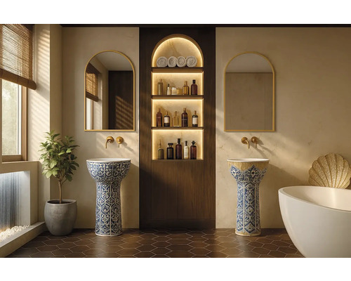 Elegantes Badezimmer mit zwei verzierten Säulenwaschbecken, Rundbogenspiegeln mit Goldrahmen, goldenen Wandarmaturen und einem Nischenregal aus Holz.