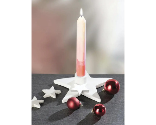 Weihnachtsdekoration mit einem weißen sternförmigen Kerzenhalter, einer brennenden Kerze, kleinen Dekosternen und roten Weihnachtskugeln.