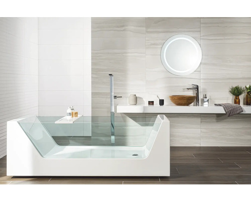 Modernes Badezimmer mit Glasbadewanne, freistehender Armatur, Aufsatzwaschbecken aus Holz und beleuchtetem Rundspiegel.