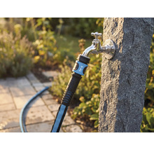 Textilschlauch mit for_q Logo an einem Außenwasserhahn an einer Steinsäule im Garten.