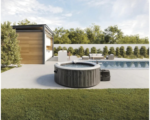 Aufblasbarer Whirlpool von Intex in Holzoptik auf einer modernen Terrasse neben einem Swimmingpool und einem Gartenhaus.