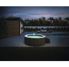 Aufblasbarer Intex Whirlpool in dunkler Holzoptik auf einer modernen Terrasse neben einem Pool bei Dämmerung mit Gartenmöbeln im Hintergrund.