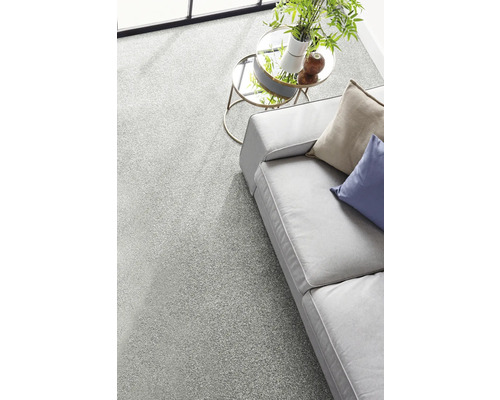 Hellgrauer Teppichboden in einem hellen, modern eingerichteten Wohnzimmer mit Sofa und runden Glastischen.