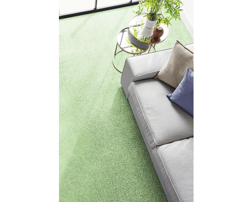 Moderner grüner Teppichboden in einem hellen Wohnzimmer mit grauem Sofa und Beistelltisch.