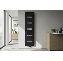 Moderner vertikaler Designheizkörper in Schwarz mit horizontalen Aussparungen an weißer Wand in einem hellen minimalistischen Raum.