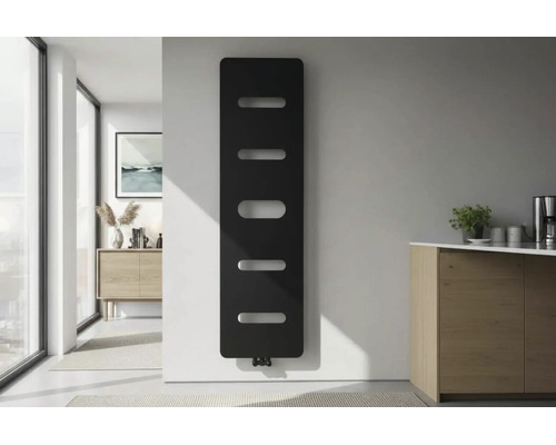 Moderner vertikaler Designheizkörper in Schwarz mit horizontalen Aussparungen an weißer Wand in einem hellen minimalistischen Raum.