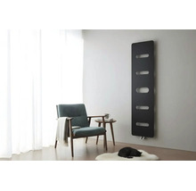 Schwarzer Designheizkörper an grauer Wand in einem hellen Wohnzimmer mit Sessel, Beistelltisch und weißem Teppich.