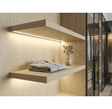 Wandregal aus hellem Holz mit integrierter LED-Beleuchtung im begehbaren Kleiderschrank, modernes Design.