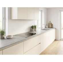 Helle moderne Küche mit cremefarbenen Fronten, grauer Arbeitsplatte in Betonoptik, Induktionskochfeld und Edelstahlspüle.