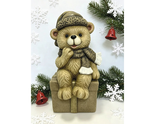 Weihnachtsfigur Teddybär sitzend auf einer Geschenkbox mit Mütze und Schal.