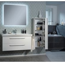 Modernes Badezimmer mit weißem Waschtischunterschrank, beleuchtetem Spiegel und geöffnetem Hochschrank mit Glasböden vor gemusterter Tapete.