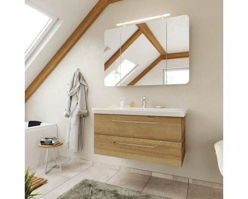 Moderner Bad-Waschtisch in Eiche-Optik mit weißem Waschbecken, dreiteiligem Spiegelschrank und Beleuchtung unter einer Dachschräge mit Holzbalken.