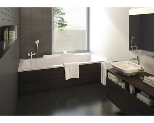 Modernes Badezimmer mit weißer Rechteck-Badewanne, dunkler Verkleidung in Holzoptik, Aufsatzwaschbecken auf dunklem Unterschrank und großem Fenster.