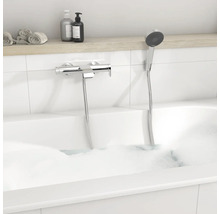 Moderne Badewannenarmatur aus Chrom mit Handbrause in einer weißen Badewanne mit Schaum.