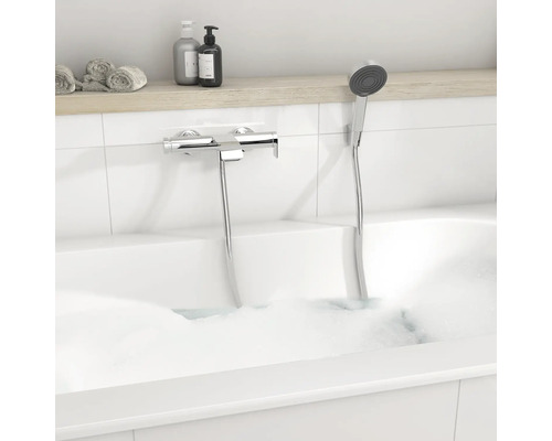 Moderne Badewannenarmatur aus Chrom mit Handbrause in einer weißen Badewanne mit Schaum.