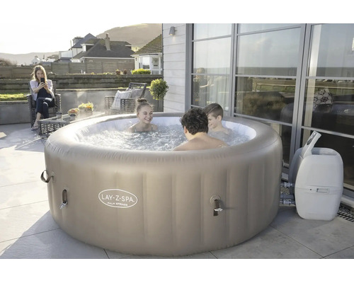 Lay-Z-Spa Palm Springs aufblasbarer Whirlpool auf einer modernen Terrasse mit drei Personen, die das sprudelnde Wasser genießen.