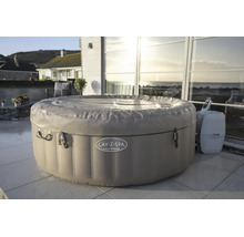 Aufblasbarer Whirlpool Lay-Z-Spa Palm Springs mit Abdeckung und Steuereinheit auf einer hellen Terrasse vor einer Glasfront.