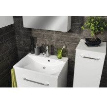 Modernes Badezimmer mit weißem Waschtischunterschrank, Waschbecken und Seitenschrank vor dunklen Wandfliesen in Steinoptik.