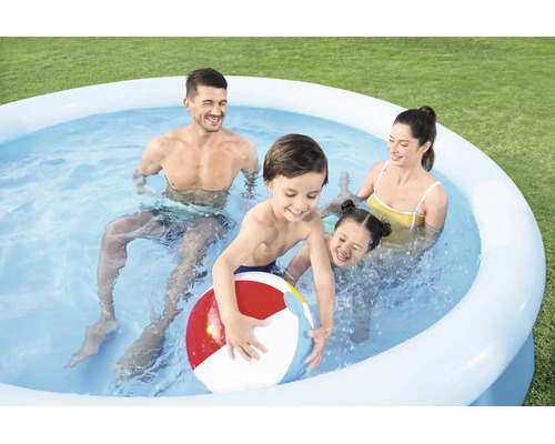Familie mit zwei Kindern spielt mit einem Wasserball in einem runden aufblasbaren Pool im Garten auf dem Rasen.