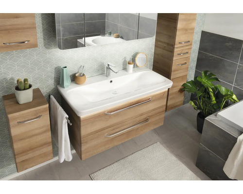 Modernes Badezimmer-Set in Eichenoptik mit weißem Waschtisch, wandhängenden Unterschränken, Spiegel und gemusterten Fliesen.